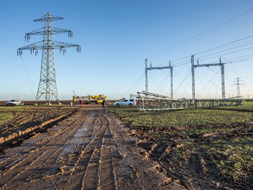 Monteure mit Kran auf einem Feld beim Netzausbau Monteure mit Kran auf einem Feld beim Netzausbau
