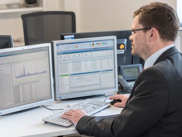 Mitarbeiter am Schreibtisch vor zwei Monitoren arbeitet am Rechner Mitarbeiter am Schreibtisch vor zwei Monitoren arbeitet am Rechner