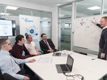 Mann hält Chart-Präsentation vor sitzender Gruppe Mann hält Chart-Präsentation vor sitzender Gruppe