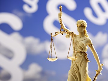 Justitia-Statue vor einem blauen Hintergrund mit weißen Paragrafenzeichen - Bildmontage Justitia-Statue vor einem blauen Hintergrund mit weißen Paragrafenzeichen - Bildmontage