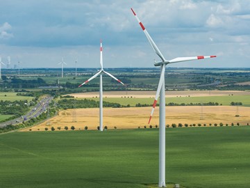 Windräder in einer Landschaft mit Feldern und Straßen Windräder in einer Landschaft mit Feldern und Straßen
