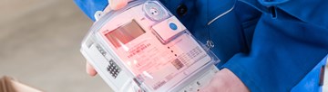 Hände mit Geräten bei der Ablesung eines Stromzählers Hände mit Geräten bei der Ablesung eines Stromzählers