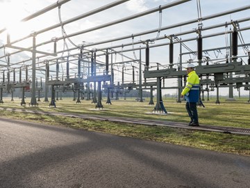 Mitarbeiter mit Helm und Warnschutzjacke bei Anlagen im Umspannwerk Mitarbeiter mit Helm und Warnschutzjacke bei Anlagen im Umspannwerk