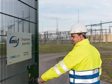 Mitarbeiter mit Helm und Warnschutzjacke am Eingangstor des Umspannwerks Jessen Mitarbeiter mit Helm und Warnschutzjacke am Eingangstor des Umspannwerks Jessen